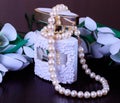 Pearl necklace and perfume on flowers background Royalty Free Stock Photo
